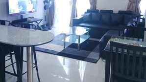A modern living room with a glass coffee table, a sofa, a dining table with chairs, a TV, and a decorative globe light. - Cubao ManhattanHeights Unit 4Q Tower D (Quezon City)