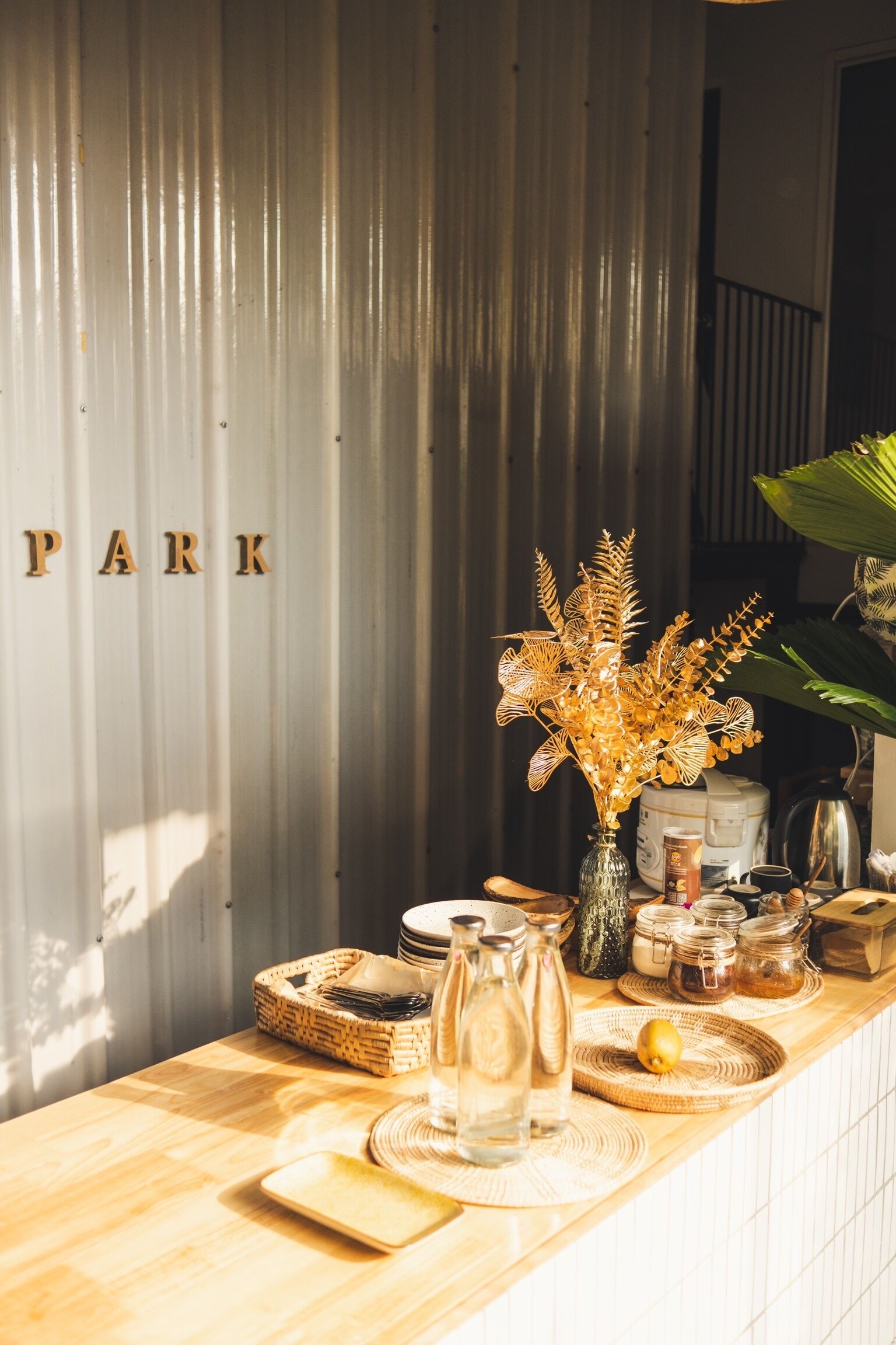 A kitchen counter with a wooden surface, a vase with dried plants, and various kitchen items.