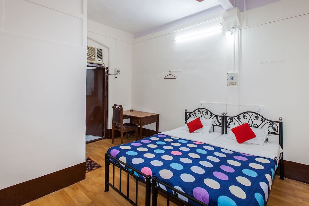 A bedroom with a bed, a desk, and a chair.