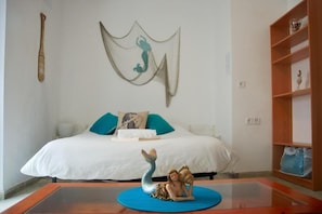 Ein Schlafzimmer mit einem Bett, einer dekorativen Meerjungfrau auf einem Tisch und einem Wandbild.
