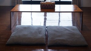 A room with a wooden floor, a table with a tissue box, and a bench outside the window. - Artisan B&B (Toucheng)