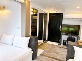 Una habitación de hotel moderna con cama, televisor, escritorio y armario.