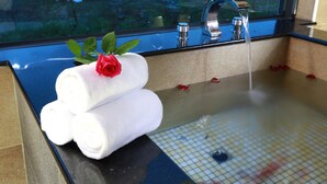 A bathroom with a glass-enclosed sink, two rolled towels, and a rose. - Artisan B&B (Toucheng)