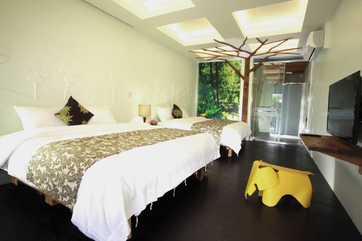 Un dormitorio con una cama grande, un televisor y un mural de un árbol en la pared.