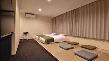 A hotel room with a bed, a desk, and a large window with curtains.