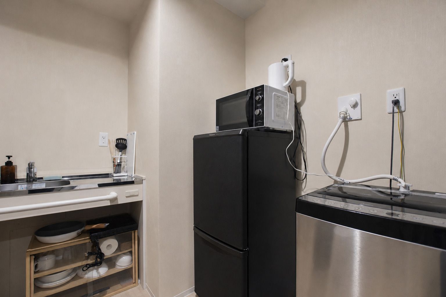 A compact kitchen with a refrigerator, microwave, and a stainless steel sink.