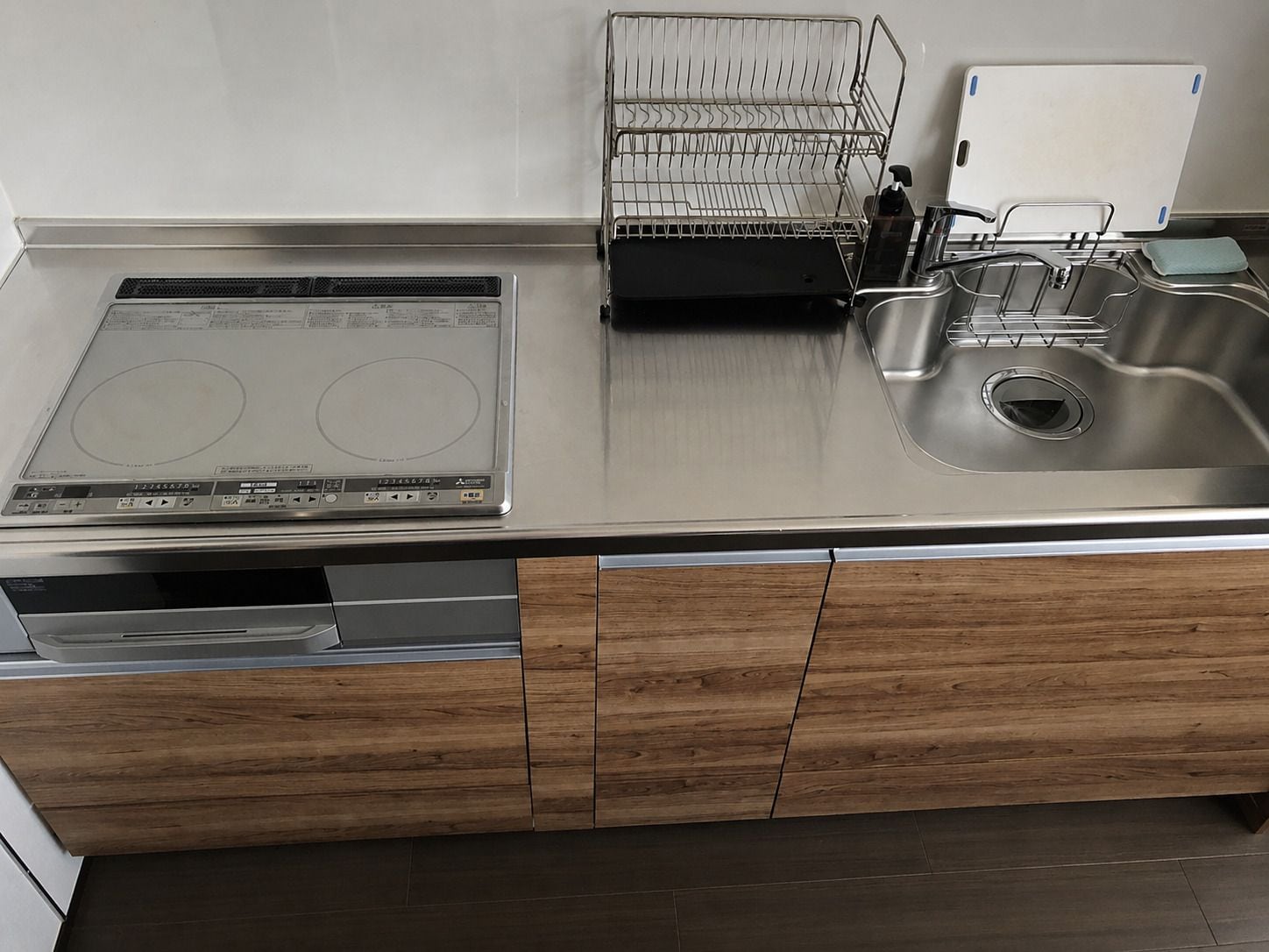 A modern kitchen with a built-in induction cooktop, a dishwasher, and a stainless steel sink.