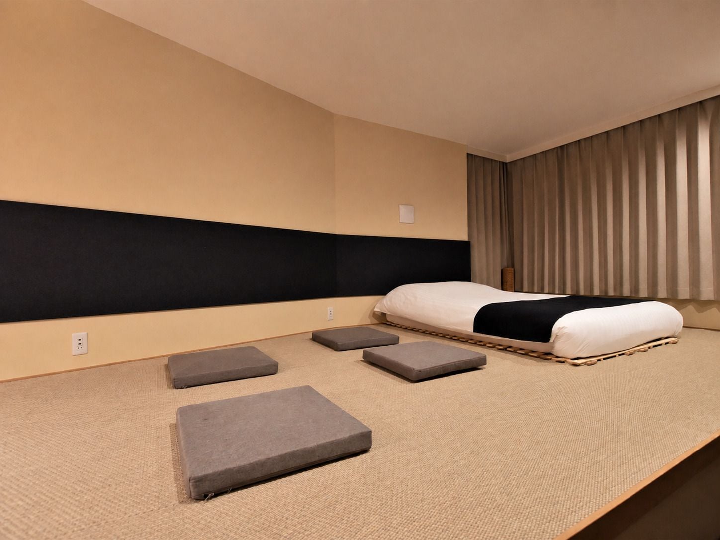 Habitación de hotel con cama, cabecera, ventana con cortinas y piso alfombrado.