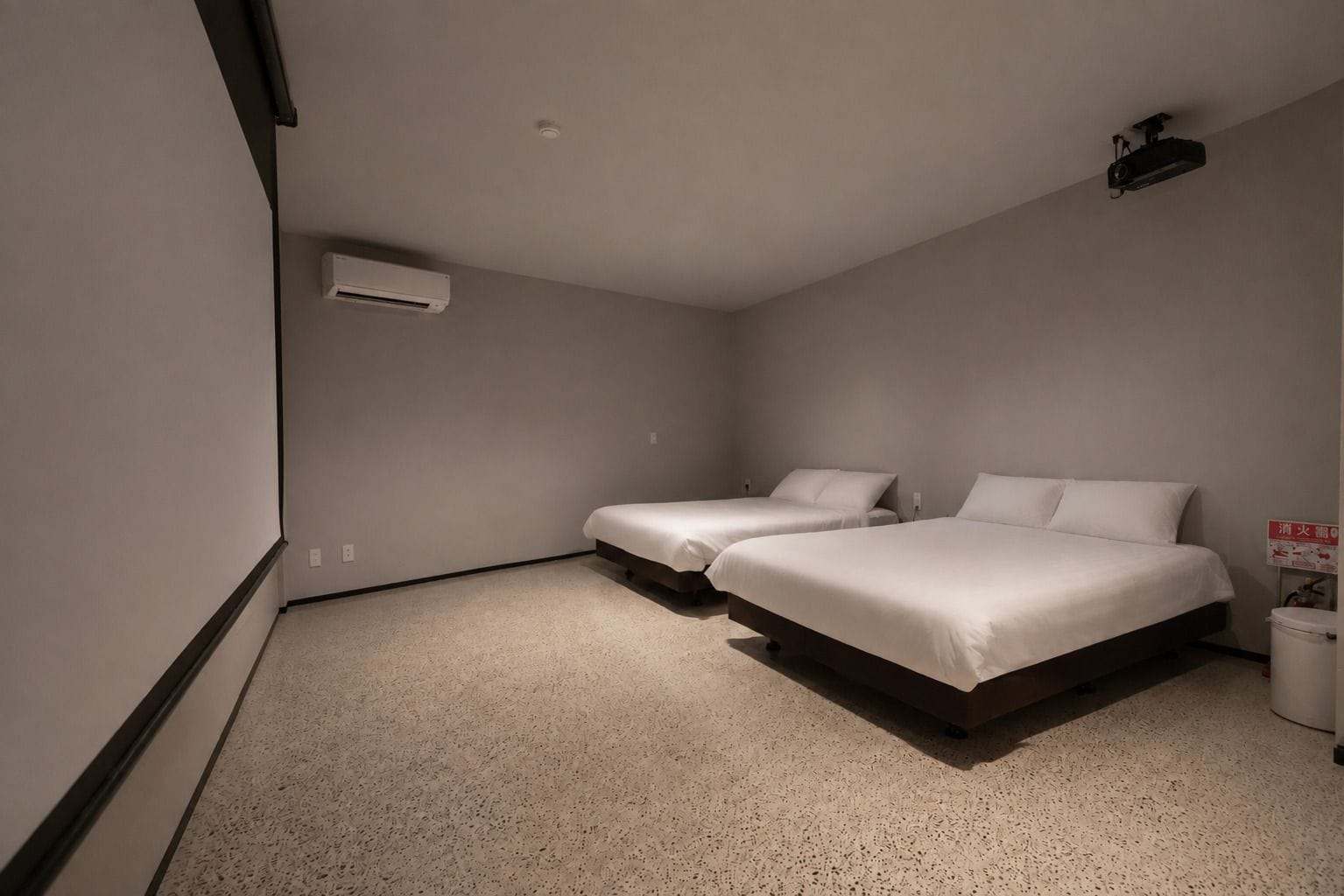 A bedroom with two beds, a ceiling projector, and a white air conditioning unit.