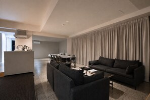 A modern living room with a sofa, a coffee table, and a dining area with a table and chairs. - Randor Residence Tokyo Suites (Tokyo)