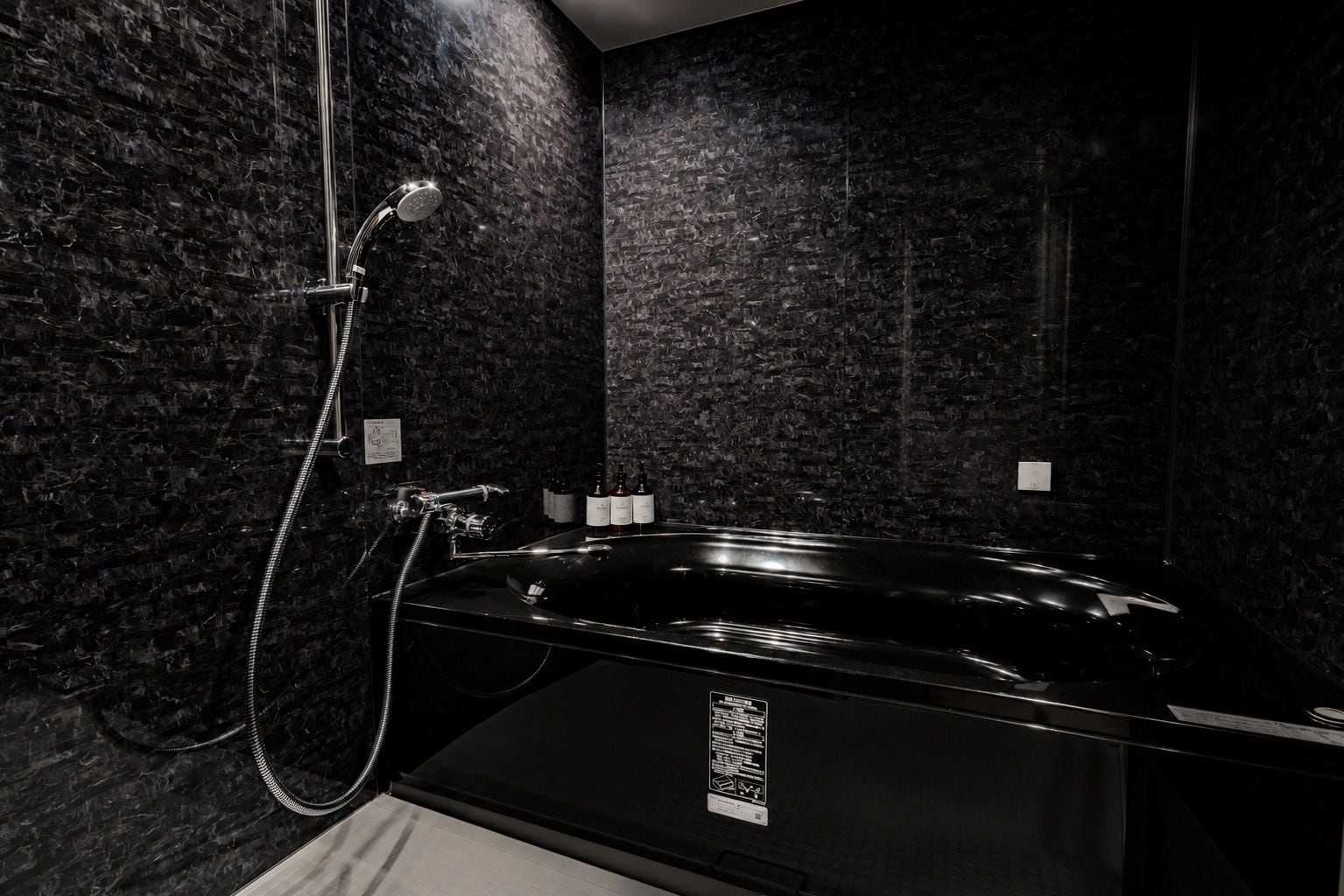 A modern bathroom with a black bathtub, a shower head, and a wall-mounted faucet.