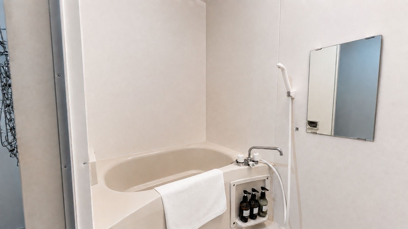 Un baño con bañera, una toalla, un espejo y un juego de artículos de aseo.