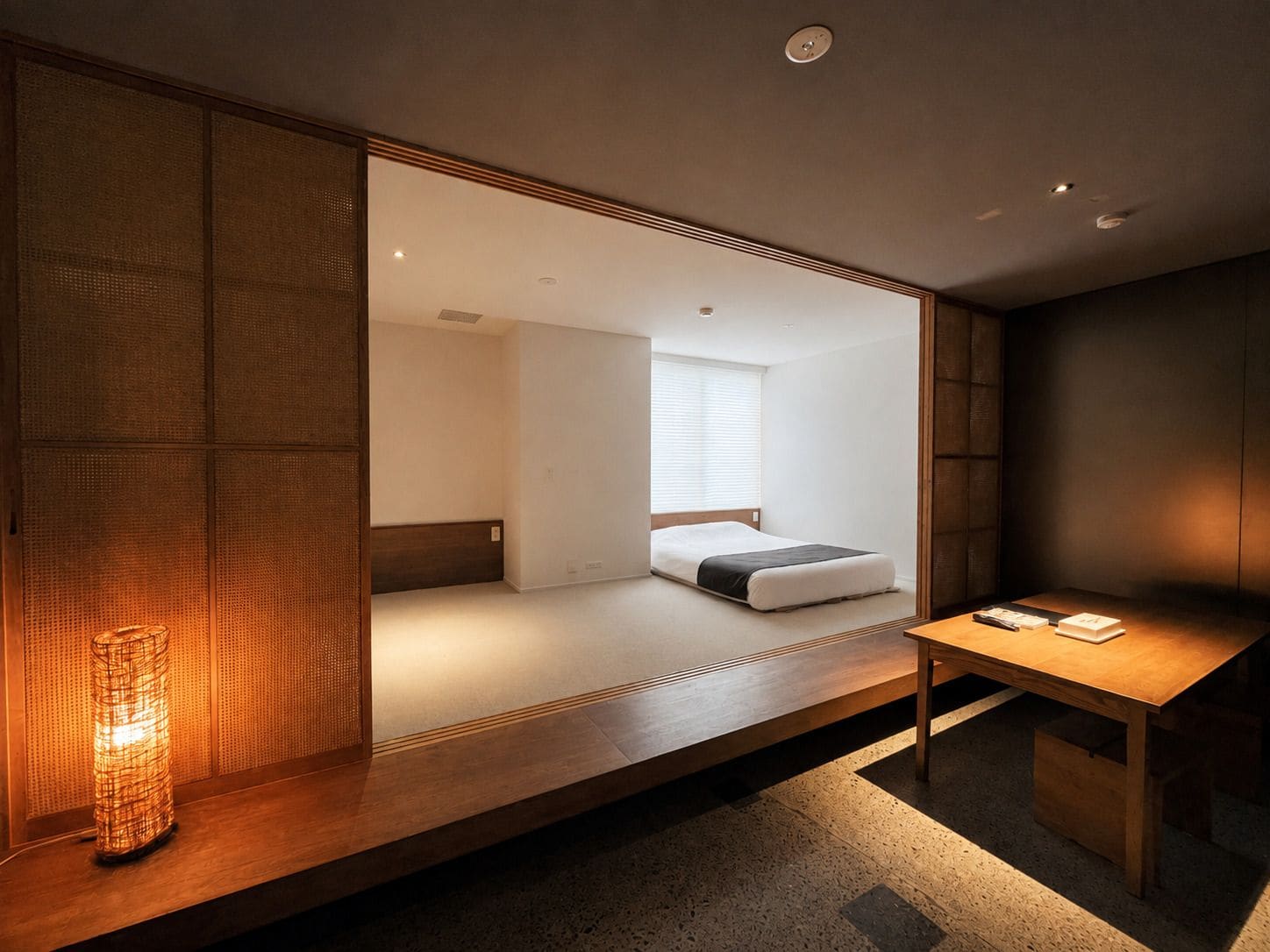 A modern room with a wooden bench, a bedside table, and a bed with a white mattress and dark bedding.