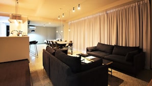A modern living room with a sofa, a coffee table, and a dining area with chairs and a table. - Randor Residence Tokyo Suites (Tokyo)