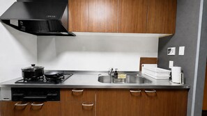 A modern kitchen with a stove, sink, and wooden cabinets. - Randor Residence Tokyo Suites (Tokyo)