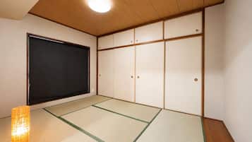A traditional Japanese room with tatami flooring, a sliding door, and a low ceiling with recessed lighting.