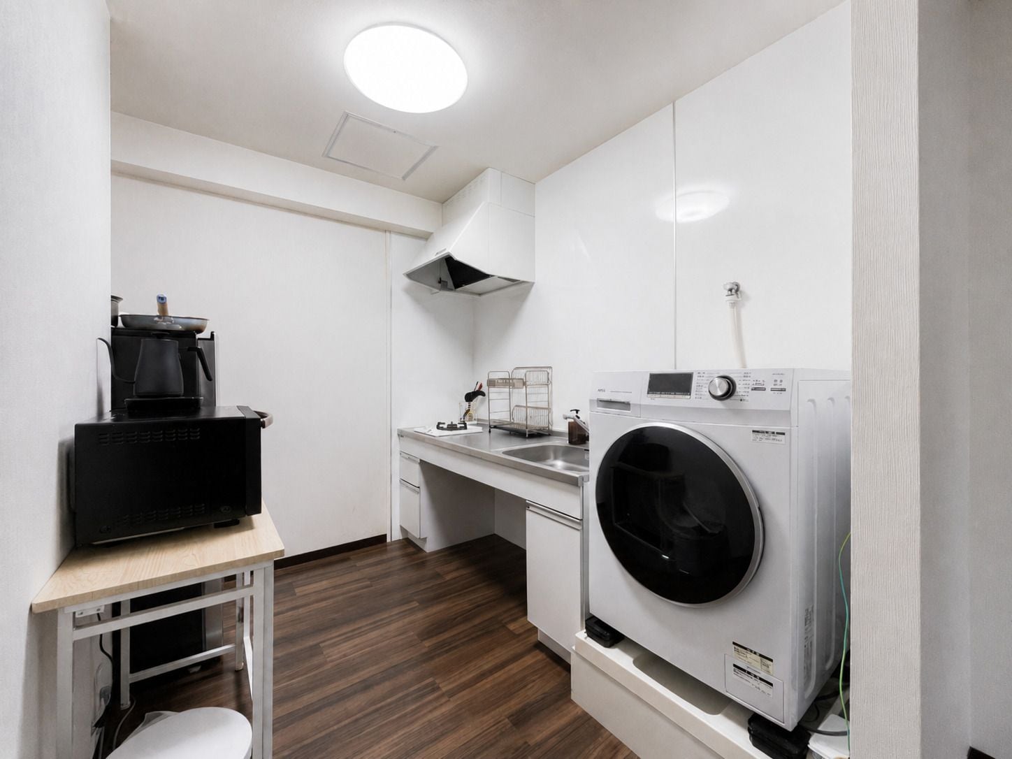 A compact kitchen with a microwave, stove, and washing machine.