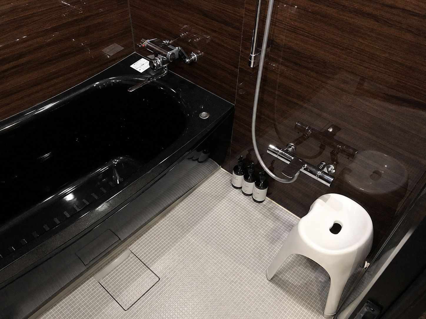 A modern bathroom with a black bathtub, a white toilet, and a shower area.