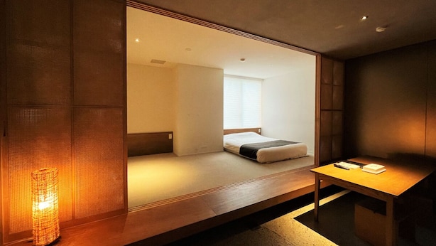 A modern hotel room with a bed, a bedside table, and a large window. - Randor Residence Tokyo Suites (Tokyo)