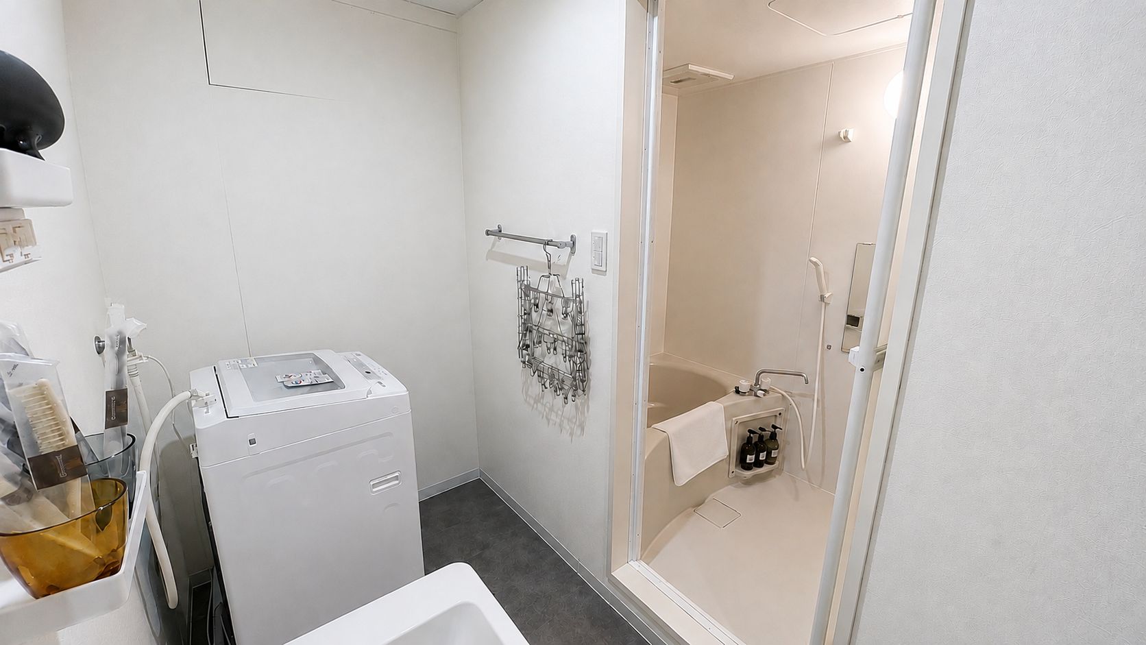 A compact bathroom with a washing machine, a shower area, and a glass-enclosed toilet.