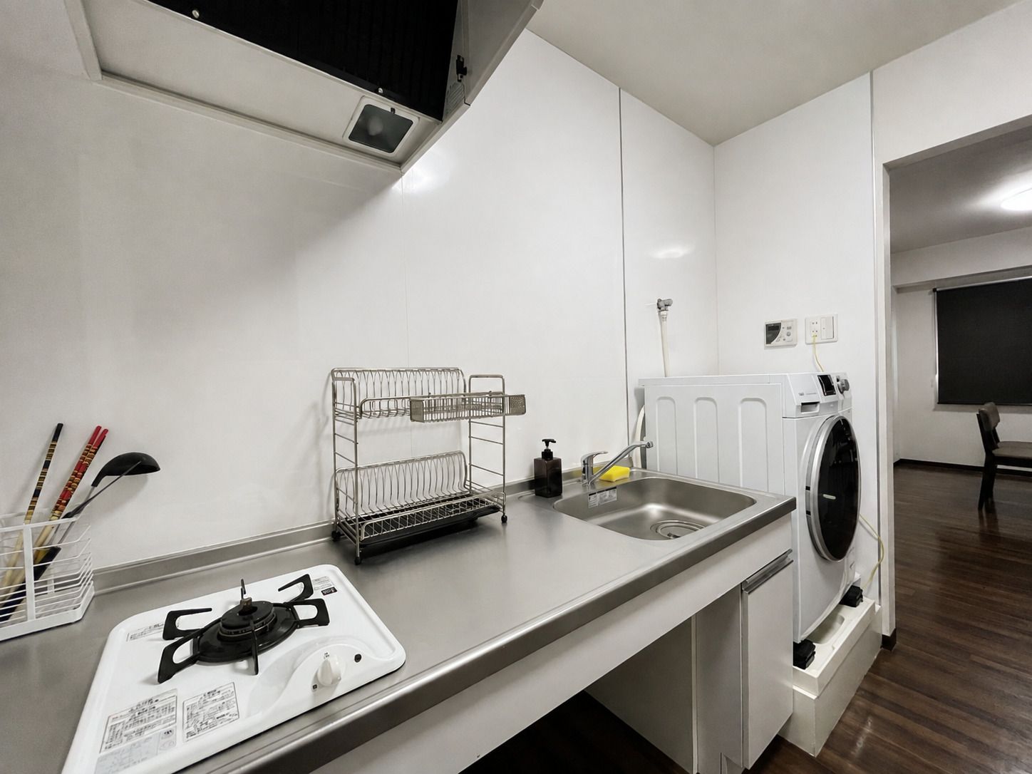 A modern kitchen with a gas stove, a sink, a dish rack, and a washing machine.
