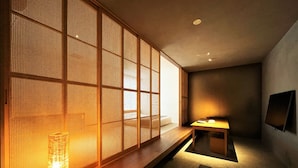 A traditional Japanese room with tatami flooring, a low wooden table, a lit candle, and a sliding shoji screen. - Randor Residence Tokyo Suites (Tokyo)