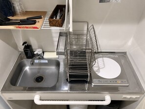 A kitchen area with a stainless steel sink, a dish rack, and a built-in stove. - Randor Residence Tokyo Suites (Tokyo)