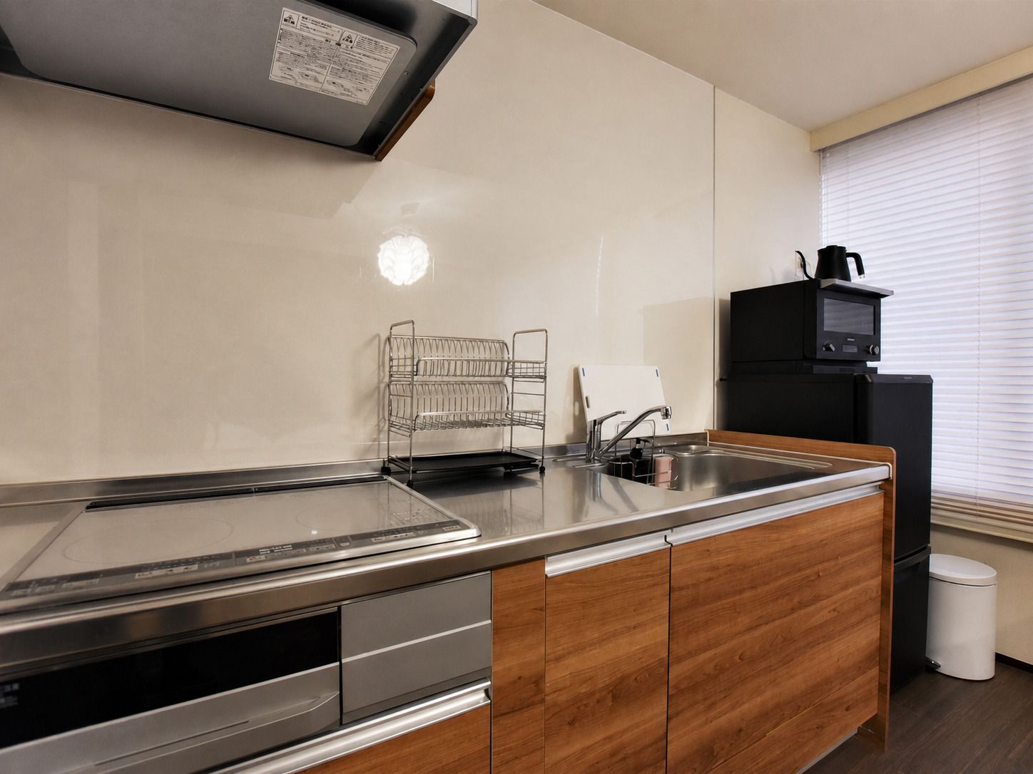 A modern kitchen with a stainless steel countertop, wooden cabinets, a built-in oven, and a microwave.