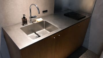 A modern kitchen with a stainless steel sink, a faucet, a soap dispenser, and a built-in induction cooktop.