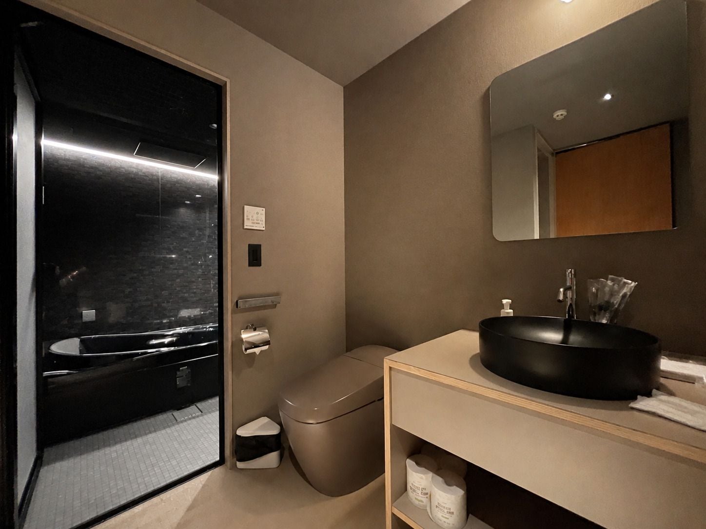 Ein modernes Badezimmer mit einem schwarzen Waschbecken, einem Spiegel und einer Toilette.