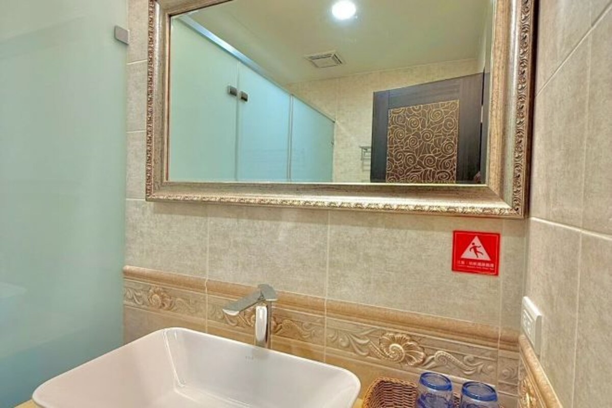 A bathroom with a white sink, a mirror, and a decorative tile backsplash.