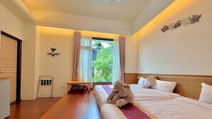 Une chambre d’hôtel avec un grand lit, une petite table, un banc et une vue sur la verdure.