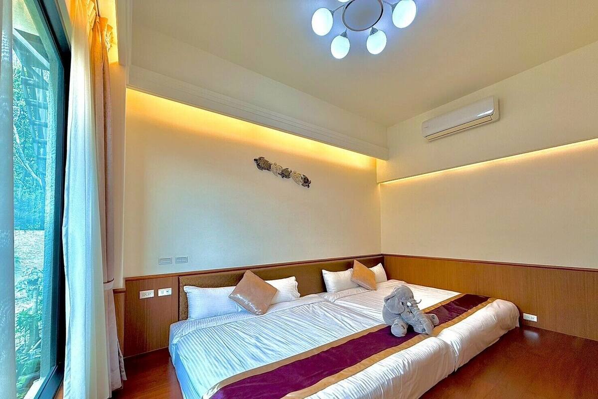 Habitación de hotel con una cama grande, una mesita de noche, un equipo de aire acondicionado y vista a zonas verdes.