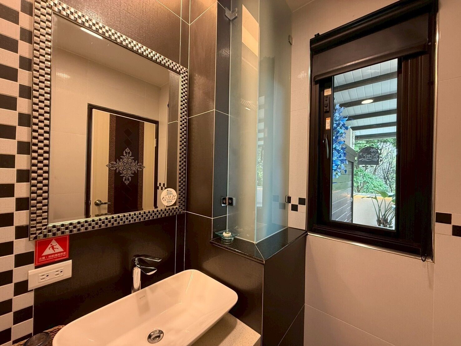 A modern bathroom with a large mirror, a sink, and a window.