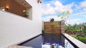 Une piscine dont le fond est recouvert de carrelage, entourée d’un mur blanc et d’une clôture en bois.