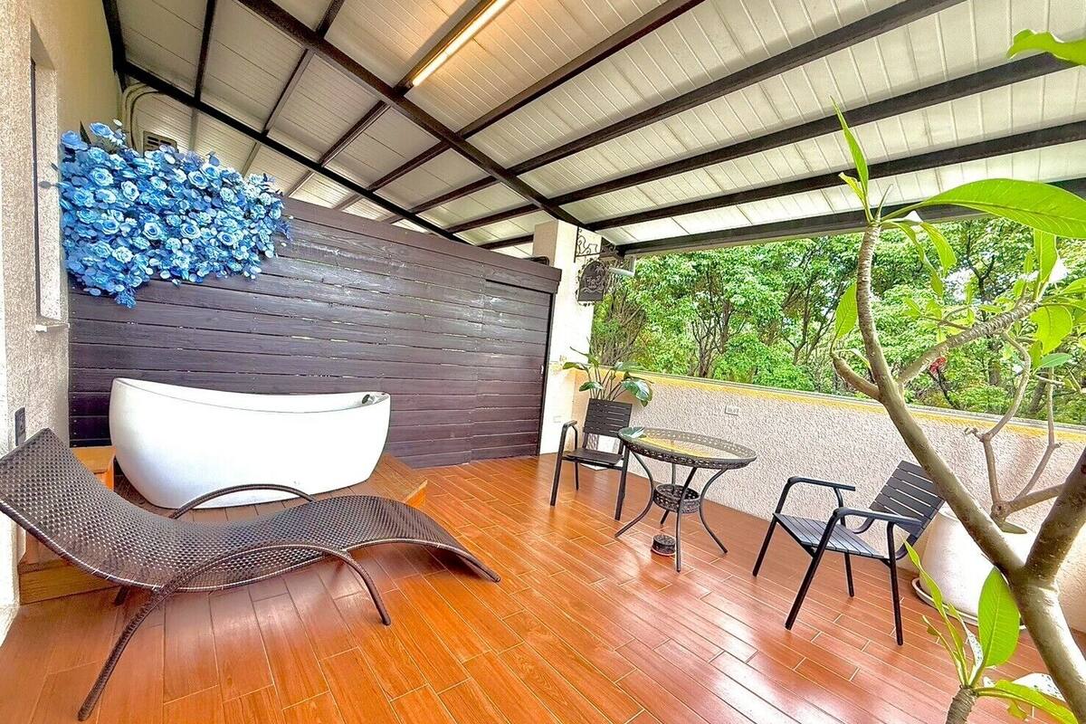 Un patio cubierto con diseño moderno, que incluye una zona de estar en forma de cuenco blanco, una pequeña mesa redonda y dos sillas.