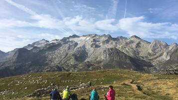 A group of people sitting on a grassy hillside with a mountainous backdrop.