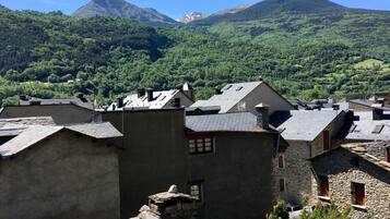 Un poble de muntanya amb cases de pedra i una muntanya destacada al fons.