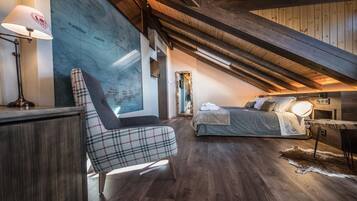 A cozy attic bedroom with a map on the wall, a bed, a chair, and a desk with a lamp.