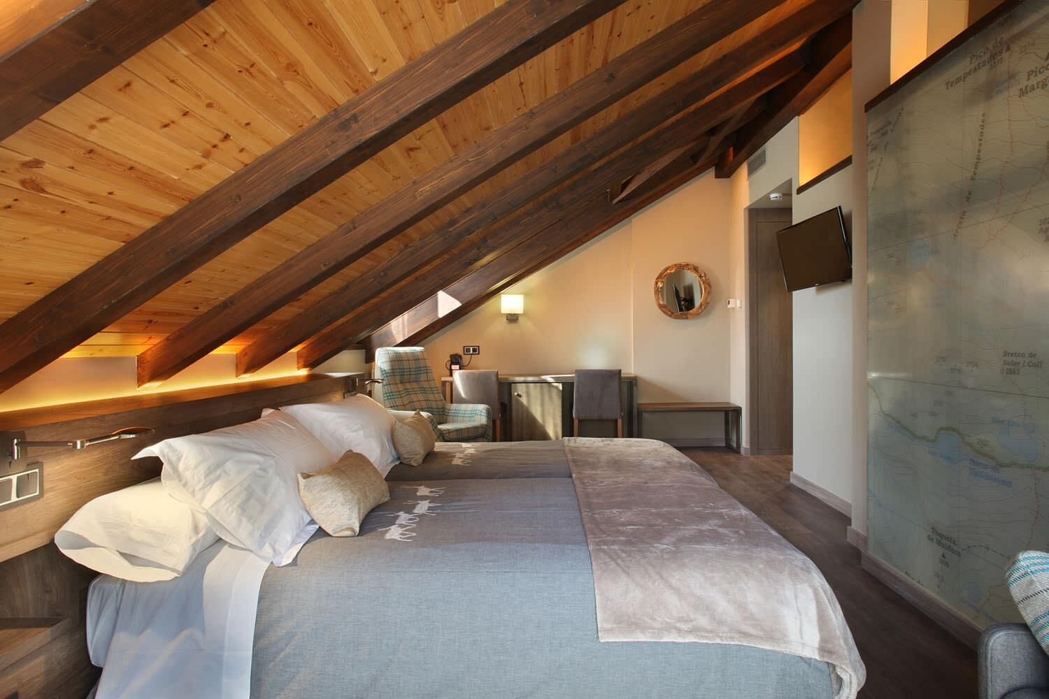 A cozy attic bedroom with a sloped ceiling, a large bed, a desk, and a map on the wall.