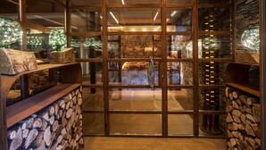 Un intérieur moderne avec une porte vitrée donnant sur une pièce chaleureuse, des étagères en bois et un mur en pierre.