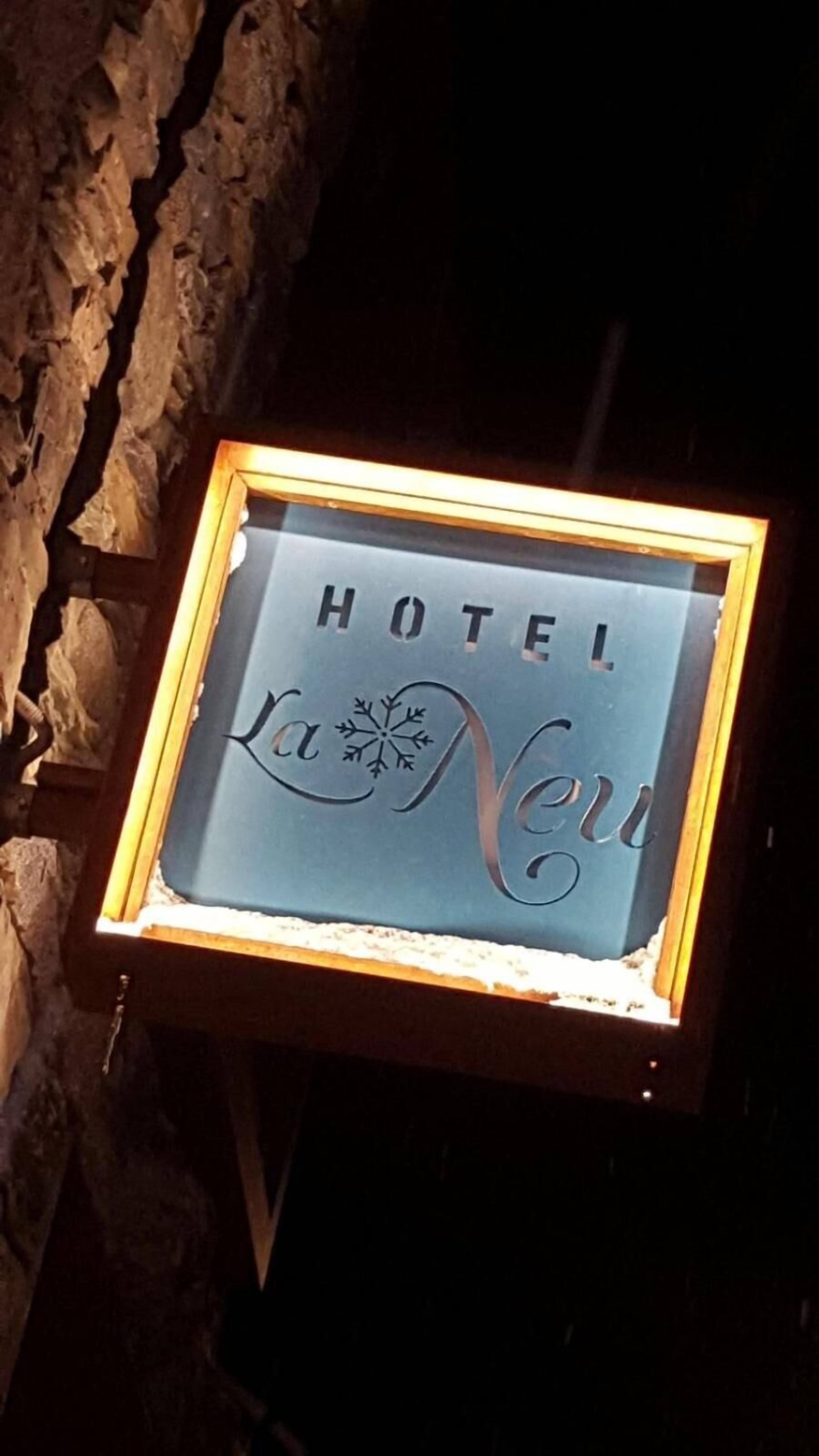 A framed sign with the words 'HOTEL La Neuv' against a stone wall background.