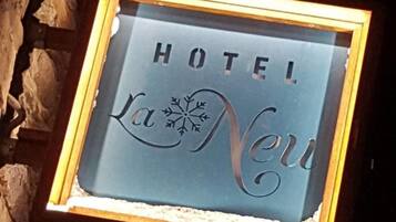 A framed sign with the words 'HOTEL La Neuv' against a stone wall background.