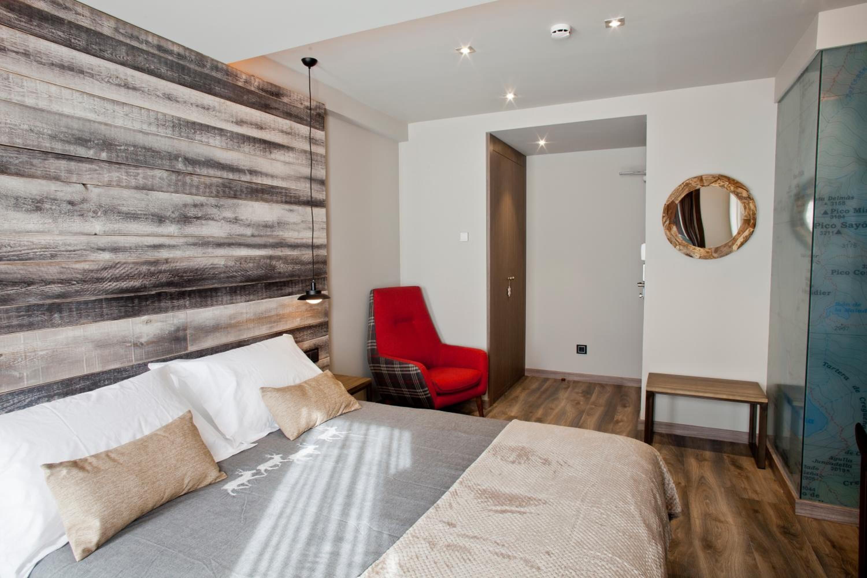 Une chambre moderne avec un grand lit, un fauteuil rouge et une carte accrochée au mur.