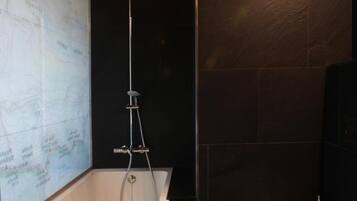 Un baño moderno con una bañera independiente, inodoro y un mapa en la pared.