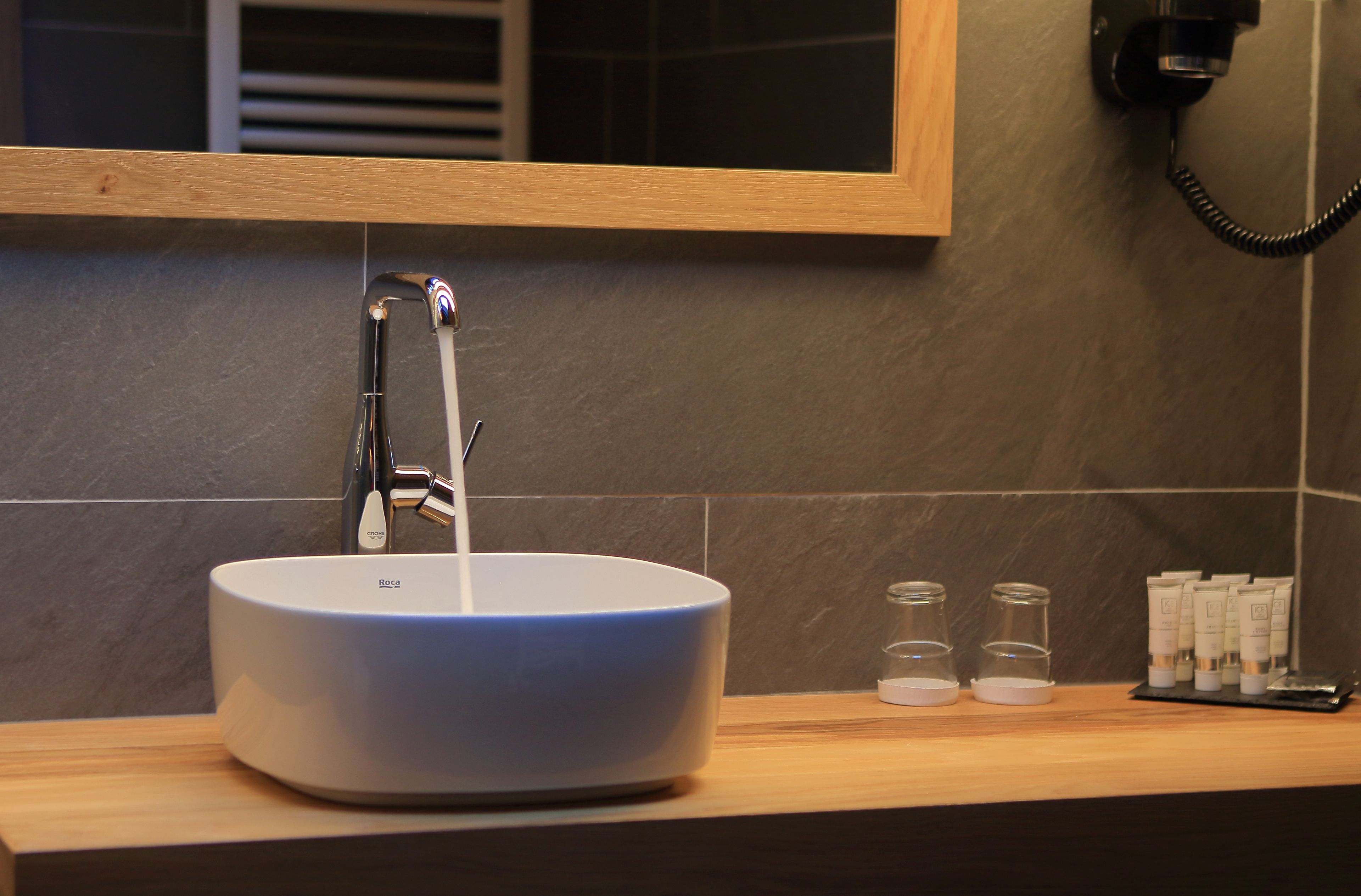 A bathroom sink with a modern faucet, a mirror above it, and toiletries on the counter.