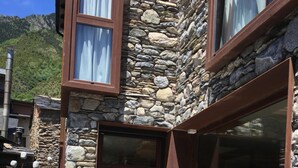 Un bâtiment en pierre doté de grandes fenêtres et d’un espace extérieur aménagé pour s’asseoir.