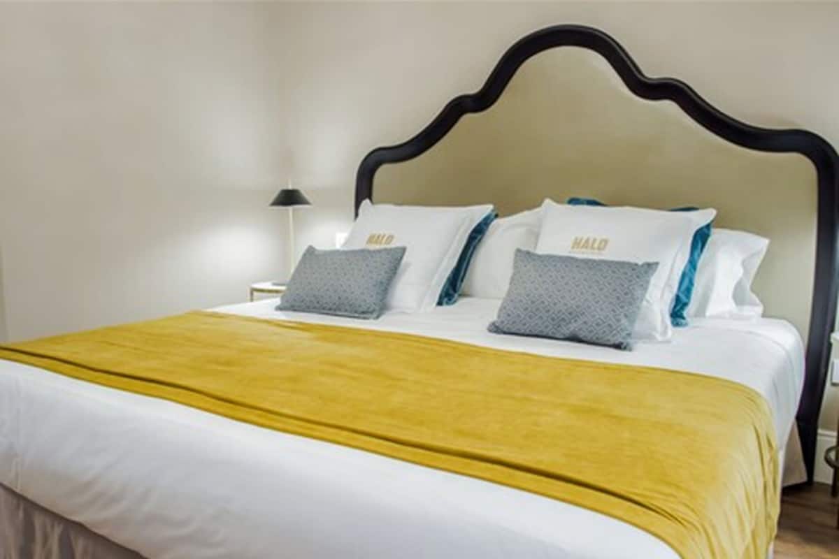 A neatly made bed with a yellow bedspread, white pillows, and a black headboard.