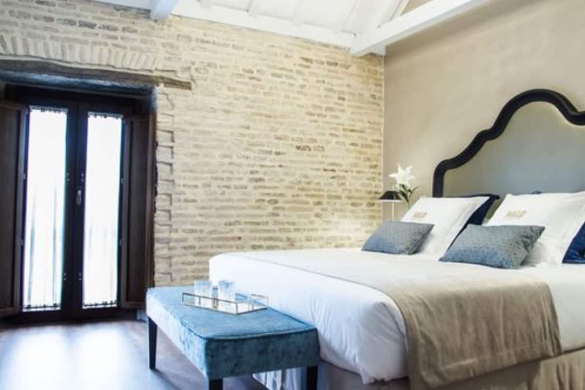 A bedroom with a large bed, a wooden headboard, and a stone wall.