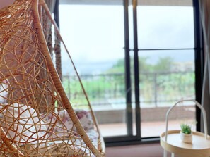 Una silla de mimbre con vistas a un balcón y una pequeña mesa con una planta.